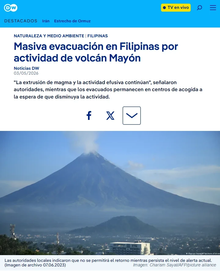 Por si creías que la cosa no podía empeorar 3 Captura de pantalla de un artículo de noticias de DW sobre la evacuación masiva en Filipinas debido a la actividad del volcán Mayón. La imagen central muestra el pico cónico del volcán con una ligera columna de humo sobre un valle habitado.